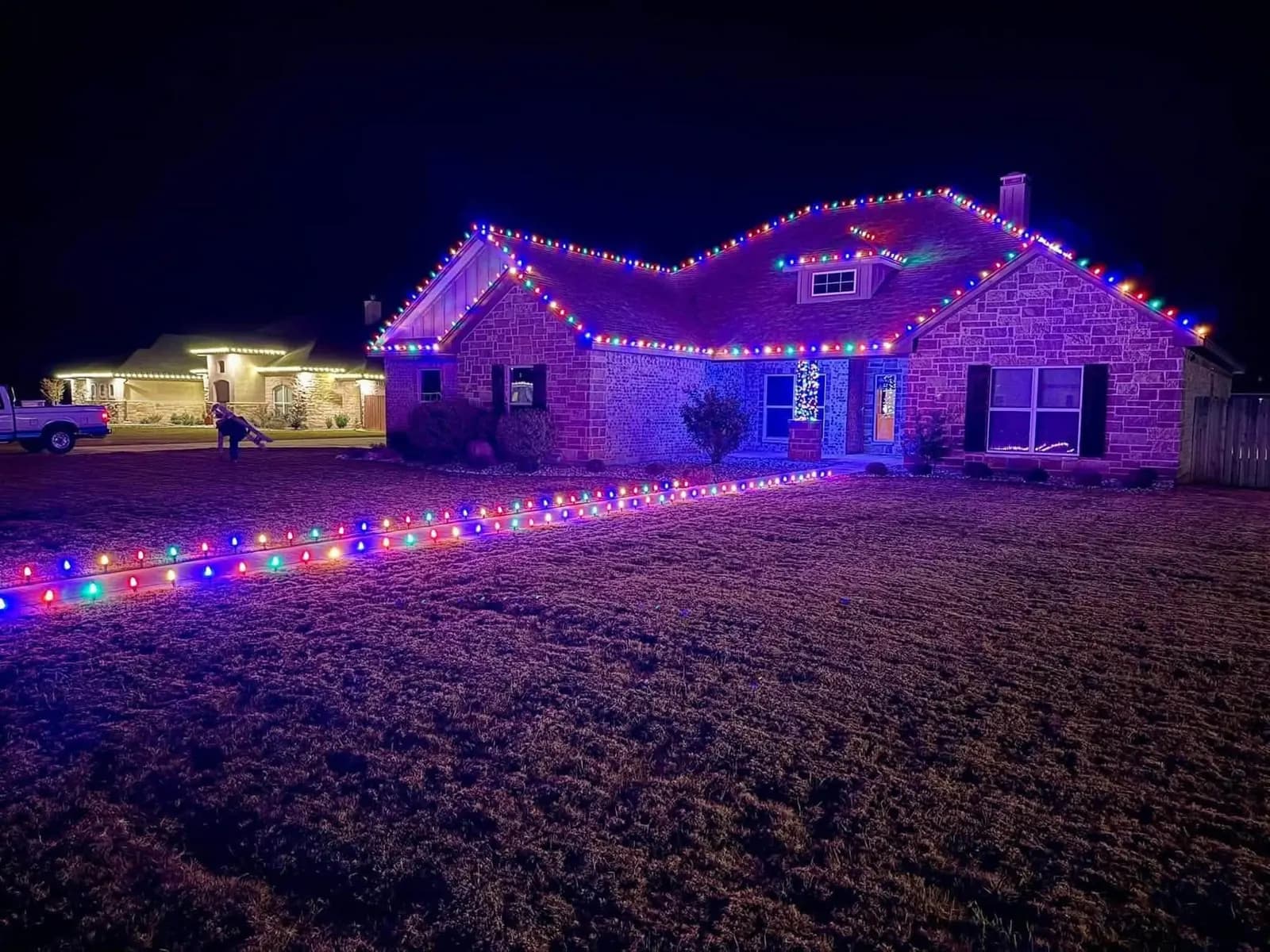 Multicolor Christmas lights outlining a home's roof peaks and front walkway